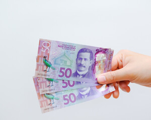 Closeup Dollar banknotes in male hand on a solid background, 50 NZ bills from New Zealand, held by a male hand on isolated white background, payday concept
