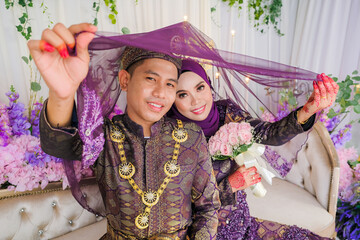 Fototapeta premium Indoor shooting for Malay wedding, the bride and groom wearing Malay traditional cloth in marriage ceremony . Happy & Family Concept.