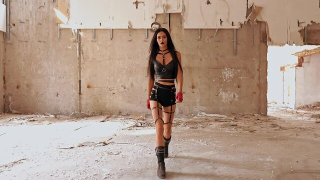 subculture concept woman with long hair wearing in leather black shorts walking to the camera slow motion interior deserted house
