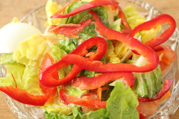 a glass bowl with fresh lettuce, bell pepper and egg