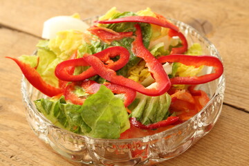 a glass bowl with fresh lettuce, bell pepper and egg