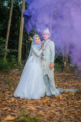 Fototapeta premium Wedding photo shooting. The bride and groom with smoke bombs on the background of trees