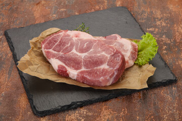 Raw pork steak over wooden board