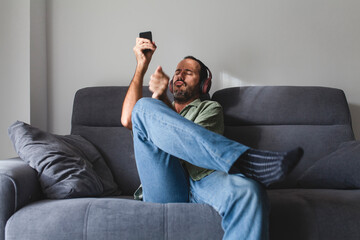 man siting on sofa listening to music and playing air drums