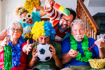 Group of crazy and coloured football supporter celebrate and exult during the match - mixed ages of caucasian people family and friends enjoy sport support activity together having fun and go for team