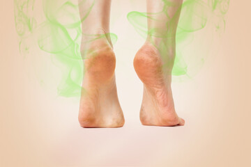 Women's feet, standing on tiptoes, showing the heel, which emanates an unpleasant smell of greenish color. Beige background. Copy space. The concept of skin diseases, foot fungus