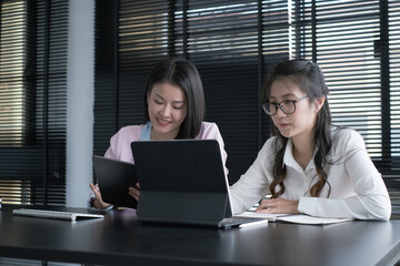 Two confident businesspeople are discussing and sharing ideas while using table in office.