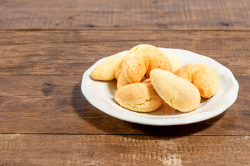 White plate with cheese, on a rustic wooden table. With space for text.