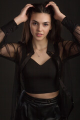 Young beautiful brunette with long hair, posing in black clothes. In a Studio photo