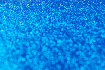 Abstract sparkling blured festive background with bokeh lights in trendy blue color for your creative design or greeting card. Festive concept or Christmas celebration