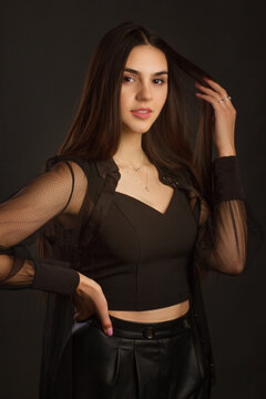 Young beautiful brunette with long hair, posing in black clothes. In a Studio photo