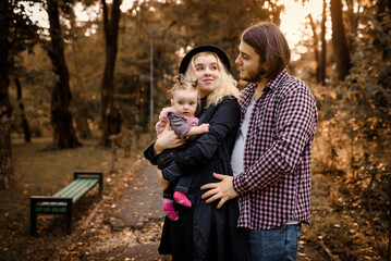  Father, mother and a 6 month old baby girl are posing in a fall park. Happy family concept