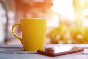 Yellow coffee cup over wooden table in front of autumnal background