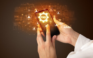 Female hand holding smartphone with FAQ abbreviation, modern technology concept