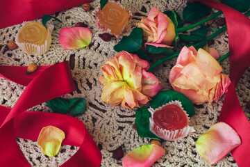 limp roses with red ribbon and marmalade on a white lace doily in vintage style