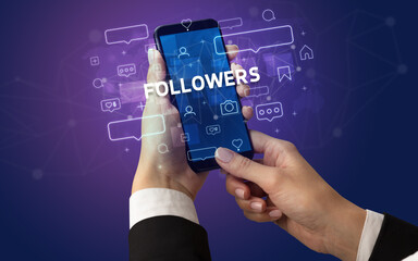Female hand typing on smartphone with FOLLOWERS inscription, social media concept