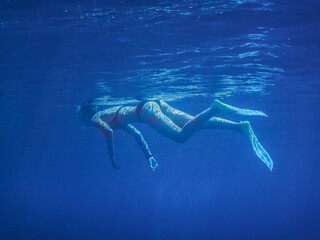 Fototapeta na wymiar woman in bikini with fins snorkeling in the blue sea