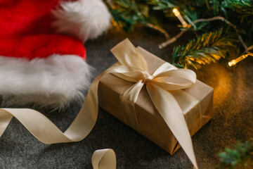 Christmas gift with Santa Claus hat and Christmas decorations on grey background with Christmas lights
