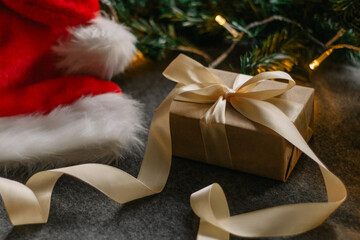 Christmas gift with Santa Claus hat and Christmas decorations on grey background with Christmas lights