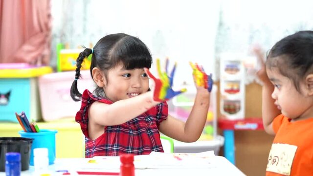 Asian cute kid girl showing a hand with colorful painting. creative girl with fun.