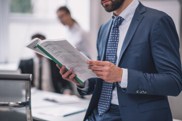 Man in suit studying document, no face visible