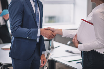 Man and woman with handshake standing in office