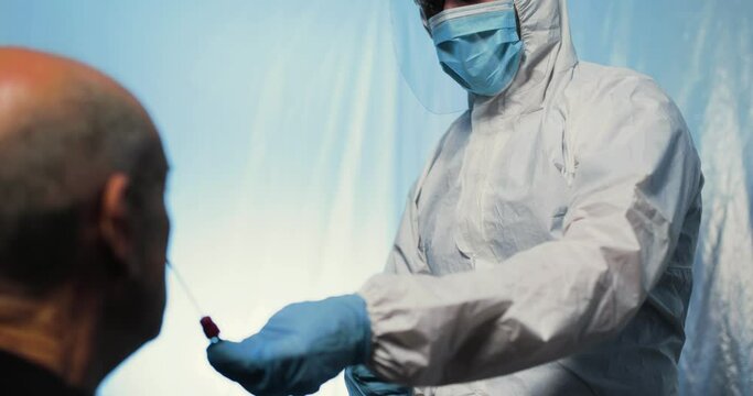 Medico con tuta bianca covid, mascherina e visiera fa il test del tampone laringeo