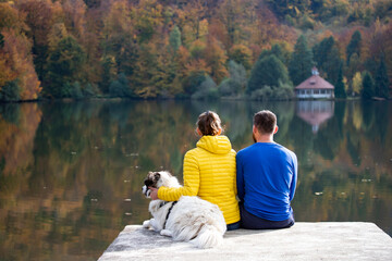 Couple in love with dog relaxing at the lake.