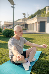 Grey-haired man sitting in lotus pose, meditating, hands in Gyan mudra