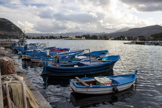 evocative image of fishing boats moored in the harbor with the coastline in the background and bad weather in the evening
