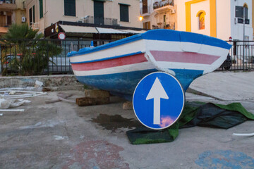 Fototapeta na wymiar curious image of a dry fishing boat with a road sign leaning on the bow