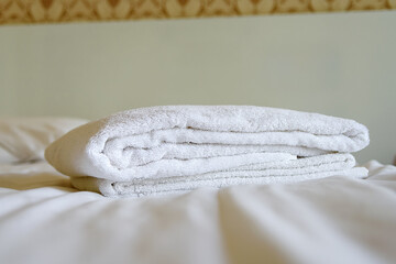 White bath towels are on the bed in the hotel