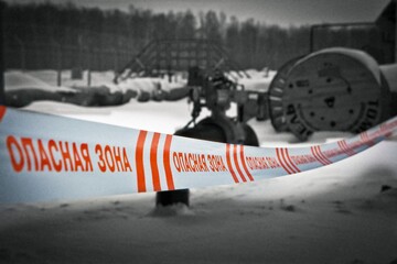 A red and white barricade tape in russian language and blurred black and white background.