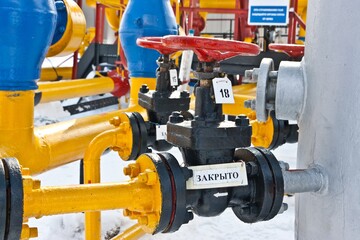 Red valves and a system of colorful pipes with signs 