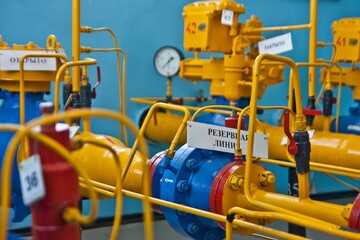 Many bright yellow pipes with red valves, bib taps and signs in Russian. Inscriptions  translated as 