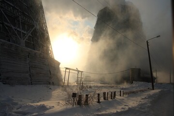 A cooling tower of a thermal power station wrapped in steam in winter.