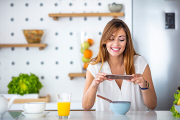 Beautiful girl taking photo of her breakfast. Dessert or food photograph hobby. Smartphone or mobile phone photography habit concept.  Young adult food stylist woman taking photo on smartphone