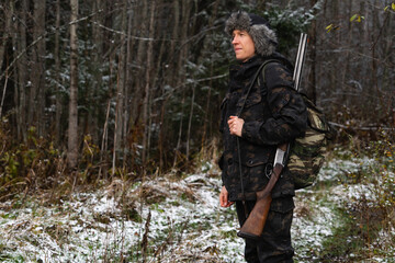 Obraz premium Hunter with a gun and a backpack in the winter forest 