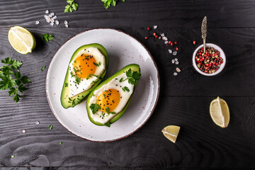 Fototapeta na wymiar Homemade Organic Egg Baked in Avocado with Salt and Pepper. Avocado stuffed with eggs. Delicious breakfast or snack. top view