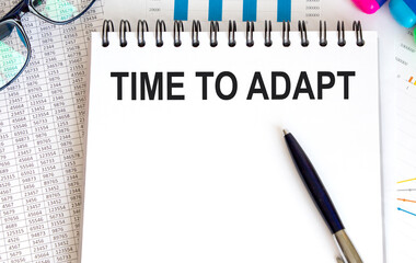 In the notebook the text of TIME TO ADAPT, next to the pen, glasses, reports.