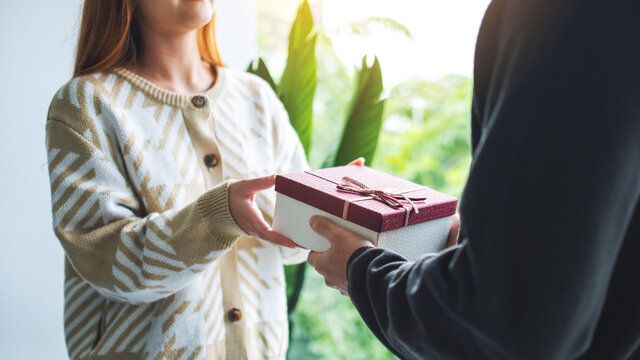 Closeup image of a man giving a woman a gift box