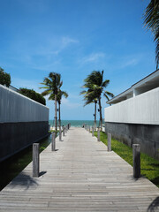 The wooden walkway leads straight to the beach on a beautiful day, making it a perfect scene for a hotel advertisement that highlights relaxation and vacation vibes.