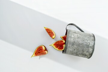Bright red ripe figs in a metal mug on a white background.