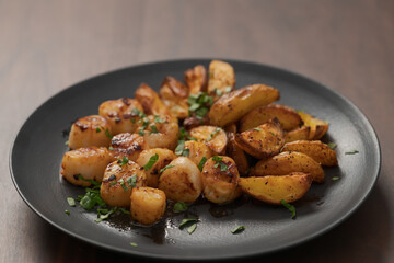 roasted scallops with baked potatoes wedges on a black plate on walnut wood background