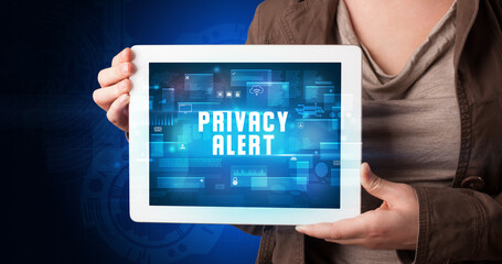 Young business person working on tablet and shows the digital sign: PRIVACY ALERT