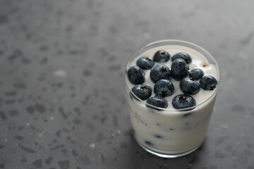 greek yogurt with blueberries and granola in glass on concrete background