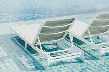 White metal recliners on pool side. Contemporary beach outdoor furniture. Swimming pool with clear blue water. Luxury vacations in Asia.