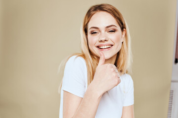 Cheerful woman in a white T-shirt gestures with her hands emotions beige background