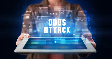 Young business person working on tablet and shows the digital sign: DDOS ATTACK