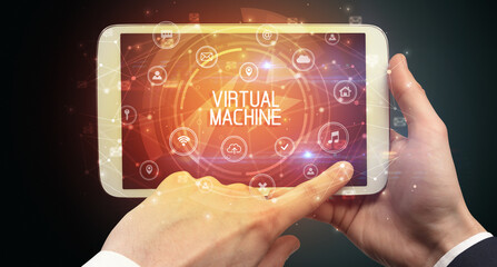 Close-up of a tablet with VIRTUAL MACHINE inscription, innovative technology concept